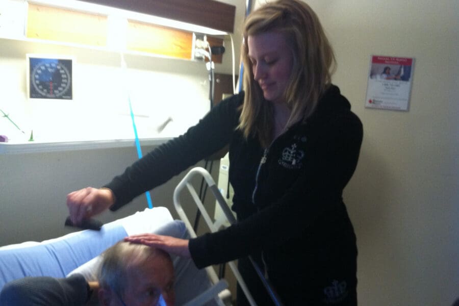 A tender moment between a young woman and her ailing grandfather in a hospital bed, symbolizing the personal struggle with deep anger and despair during the grieving process.