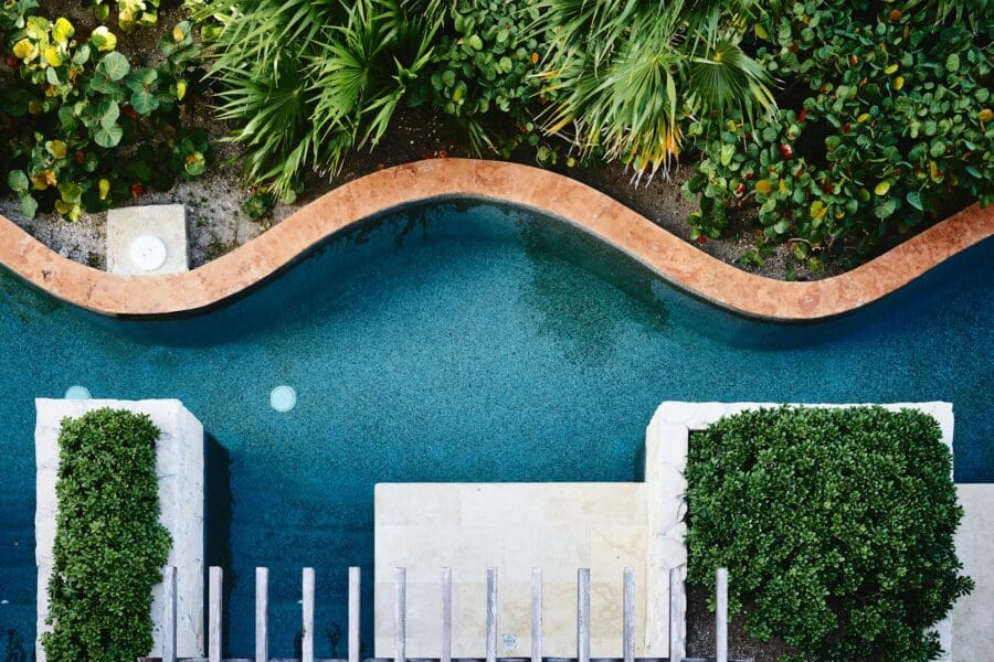 Overhead view of a winding pool surrounded by lush greenery, symbolizing the non-linear path of grief intertwined with growth and renewal.