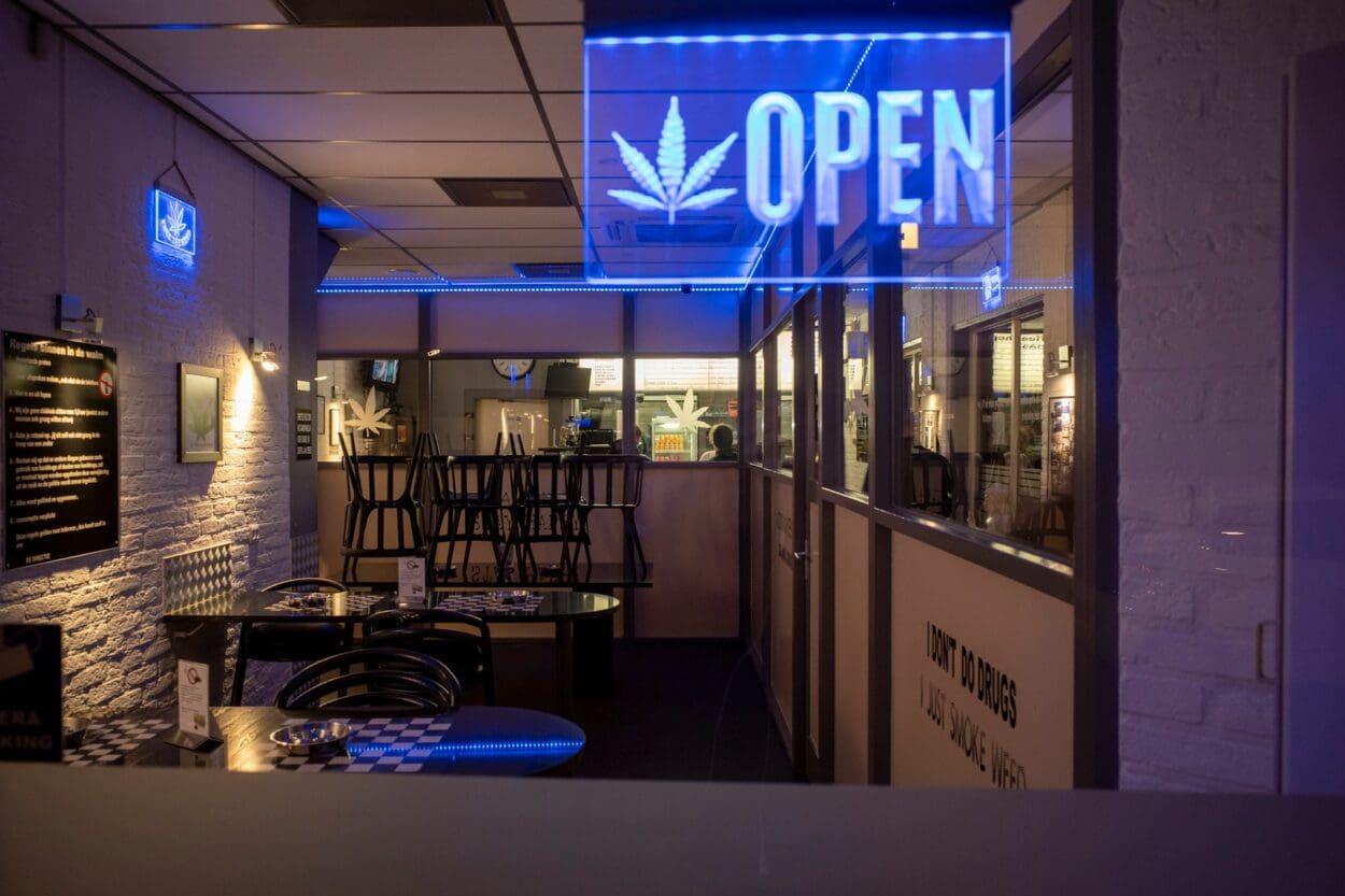 Interior of a cannabis dispensary with a neon 'OPEN' sign, symbolizing the discussion around cannabis as a potential aid in managing grief or as a temporary relief.