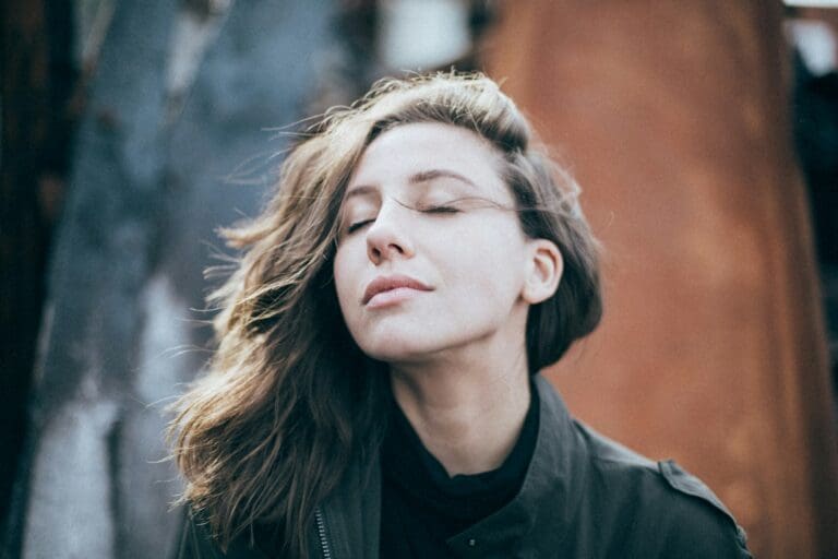 Close-up of a woman with eyes closed and taking a deep breath, symbolizing the calming and healing power of breathwork for those grieving.