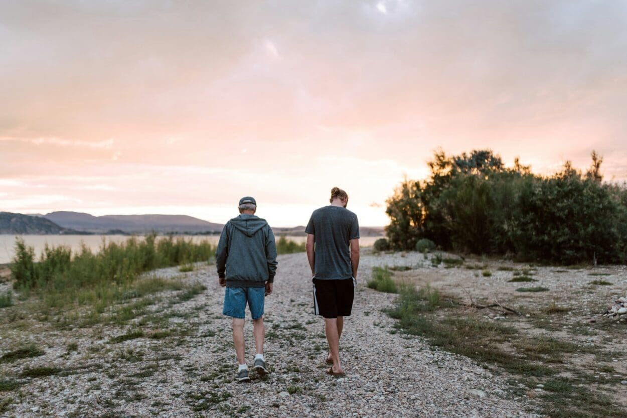 Two people walking side by side along a gravel path at sunset, symbolizing the journey of grief and the importance of empathy and support during difficult times.