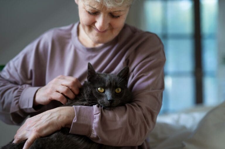 A woman gently holding a black cat, reflecting the deep bond and love shared with a pet, symbolizing the profound grief that accompanies the loss of a beloved animal companion.