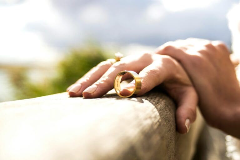 Close-up of a hand holding a wedding ring, symbolizing the emotional journey and grief associated with life after divorce.