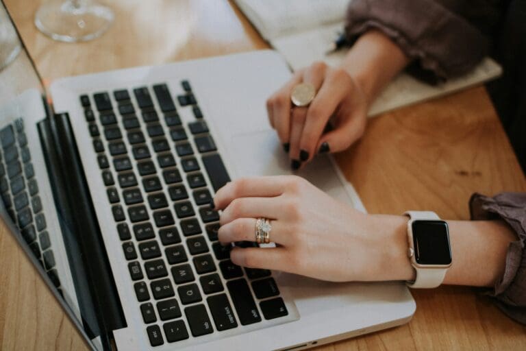 Close-up of a woman's hands typing on a laptop, symbolizing the challenge of managing grief while maintaining professionalism at work.