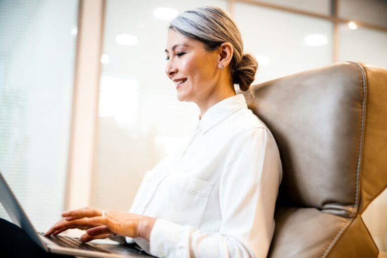 Mature businesswoman working on a laptop, embodying leadership and resilience while navigating personal challenges.