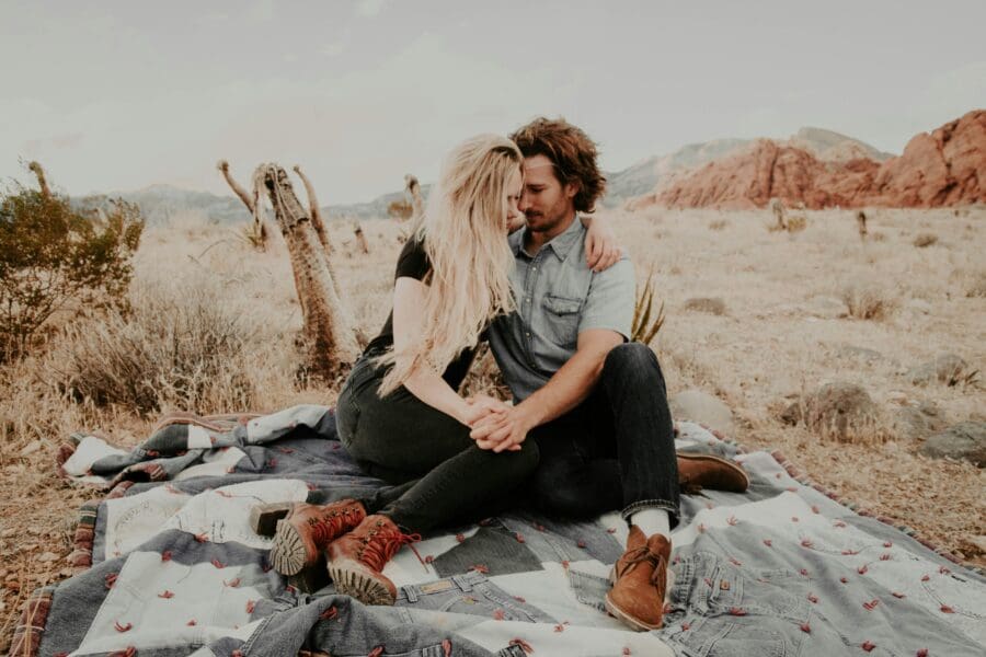 Affectionate couple embracing on a blanket in a desert setting, symbolizing support and intimacy in a relationship where one partner is managing Borderline Personality Disorder and grief.