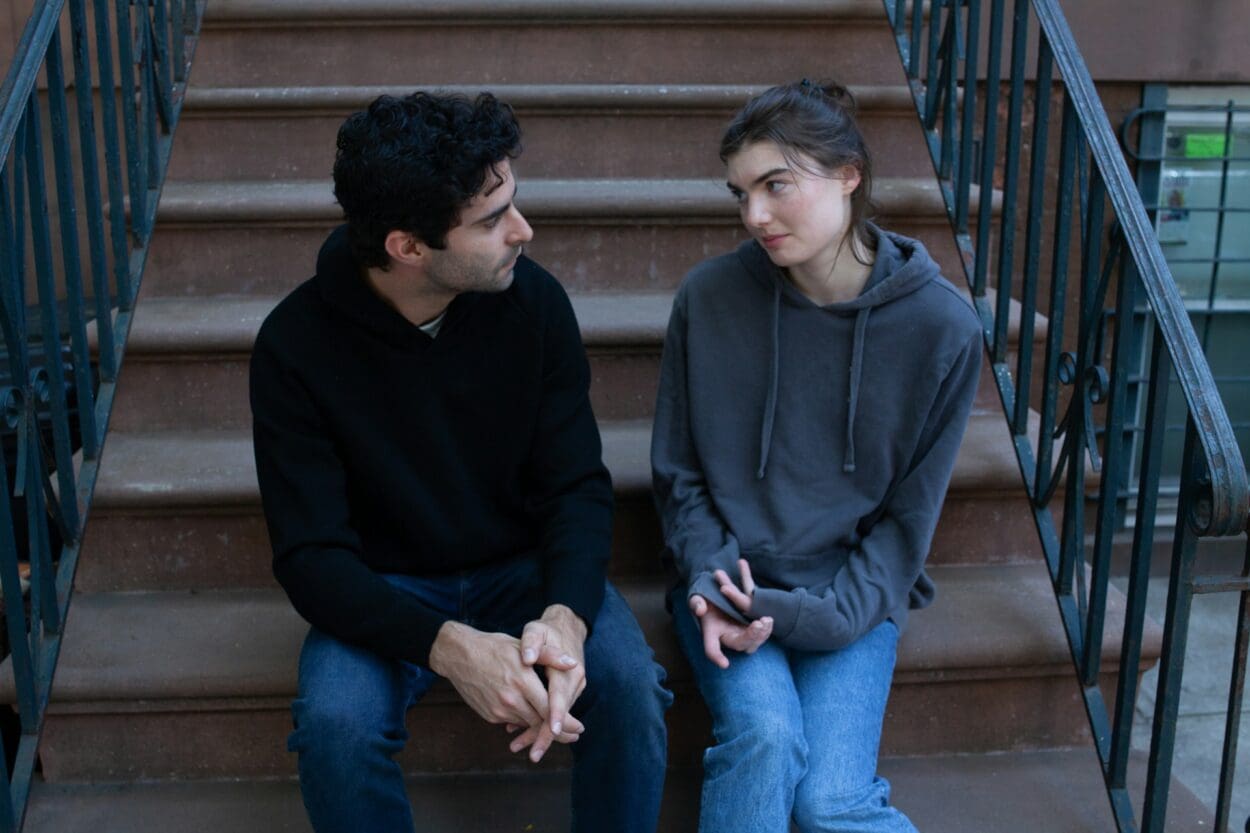 Two people sitting on a city stairway in conversation, illustrating a moment of support and understanding during the emotional challenges of a breakup, especially when dealing with Borderline Personality Disorder.