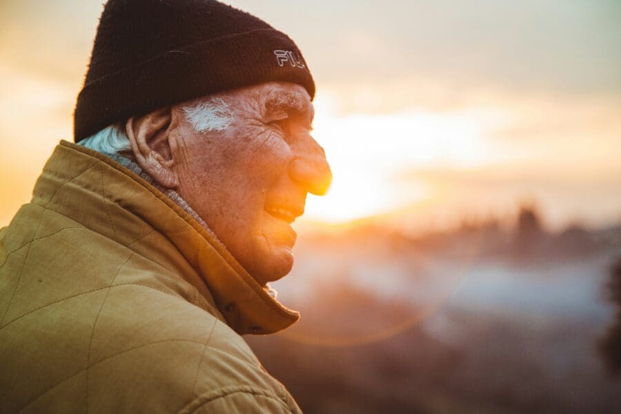 An elderly man gazing into the sunset, symbolizing the complex emotions experienced while grieving the progressive loss of a father to dementia.