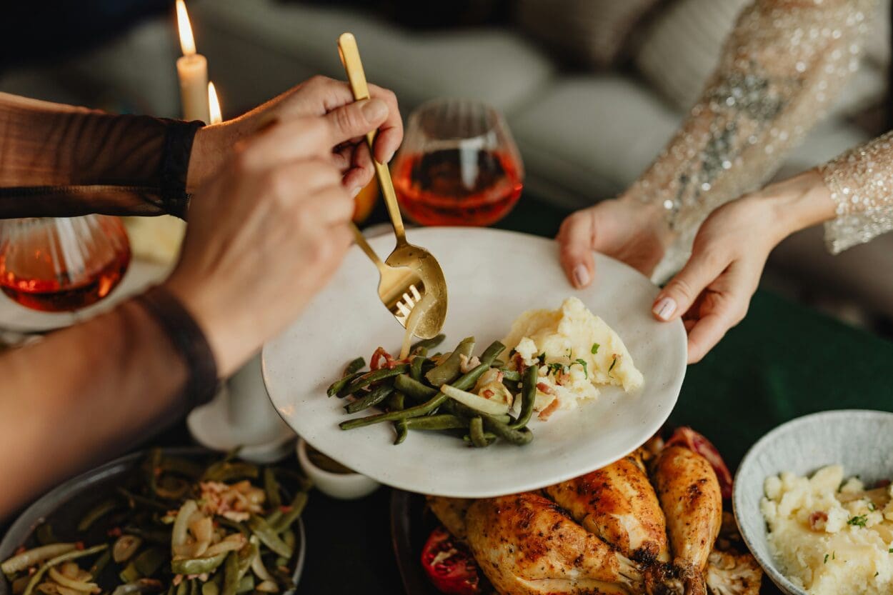 Family gathering around a festive table, sharing a holiday meal together, symbolizing the challenge of navigating traditions and maintaining connections during grief and loss.