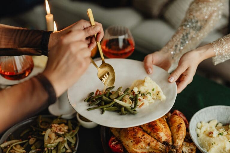 Family gathering around a festive table, sharing a holiday meal together, symbolizing the challenge of navigating traditions and maintaining connections during grief and loss.