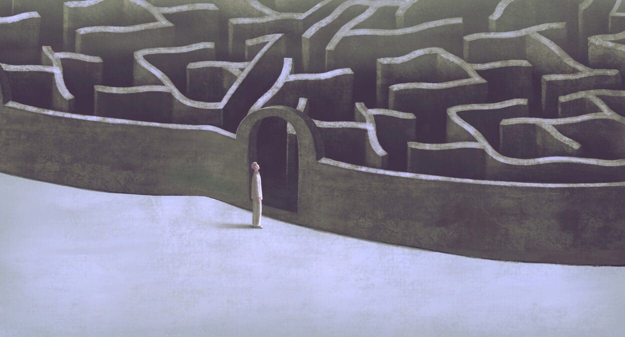 A figure stands at the entrance of a complex maze, symbolizing the daunting and intricate journey through the psychological impacts of losing a loved one to suicide.